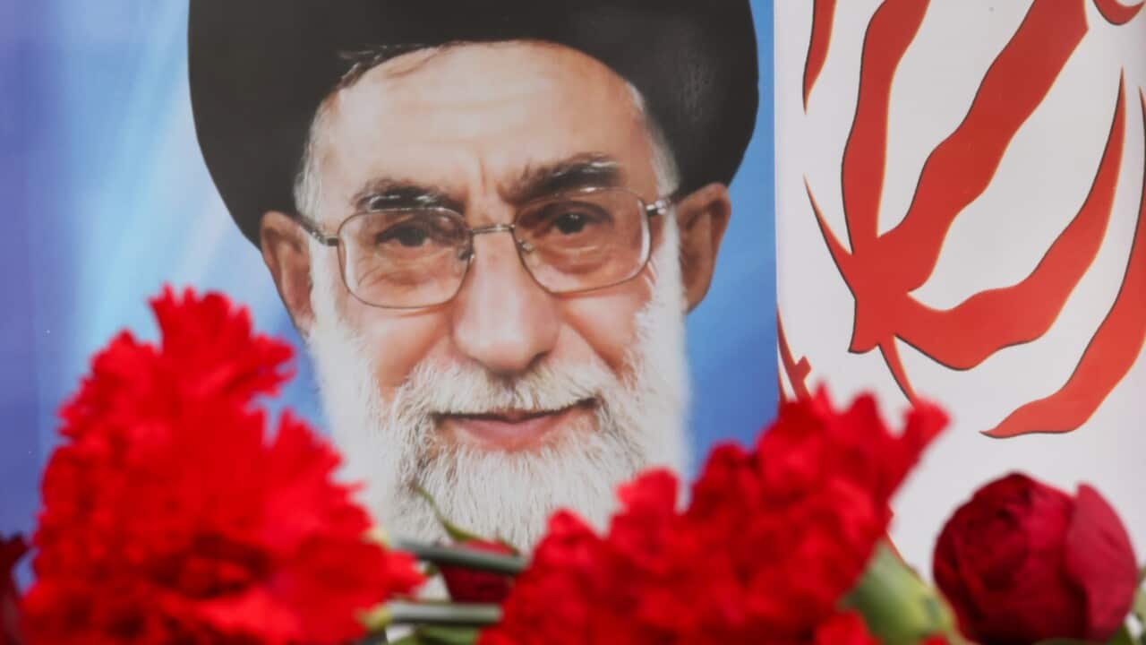 red flowers, blurred, placed in front of an image of the Ali Khamenei.