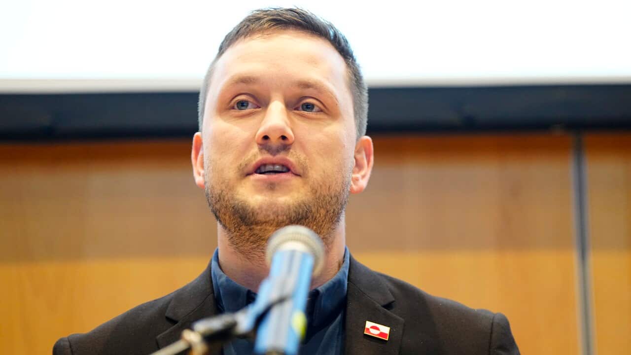 A man in a suit speaks at a microphone.