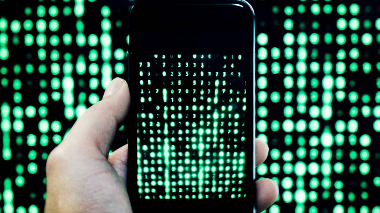 Cropped Hand Of Man Holding Mobile Phone With Binary Code