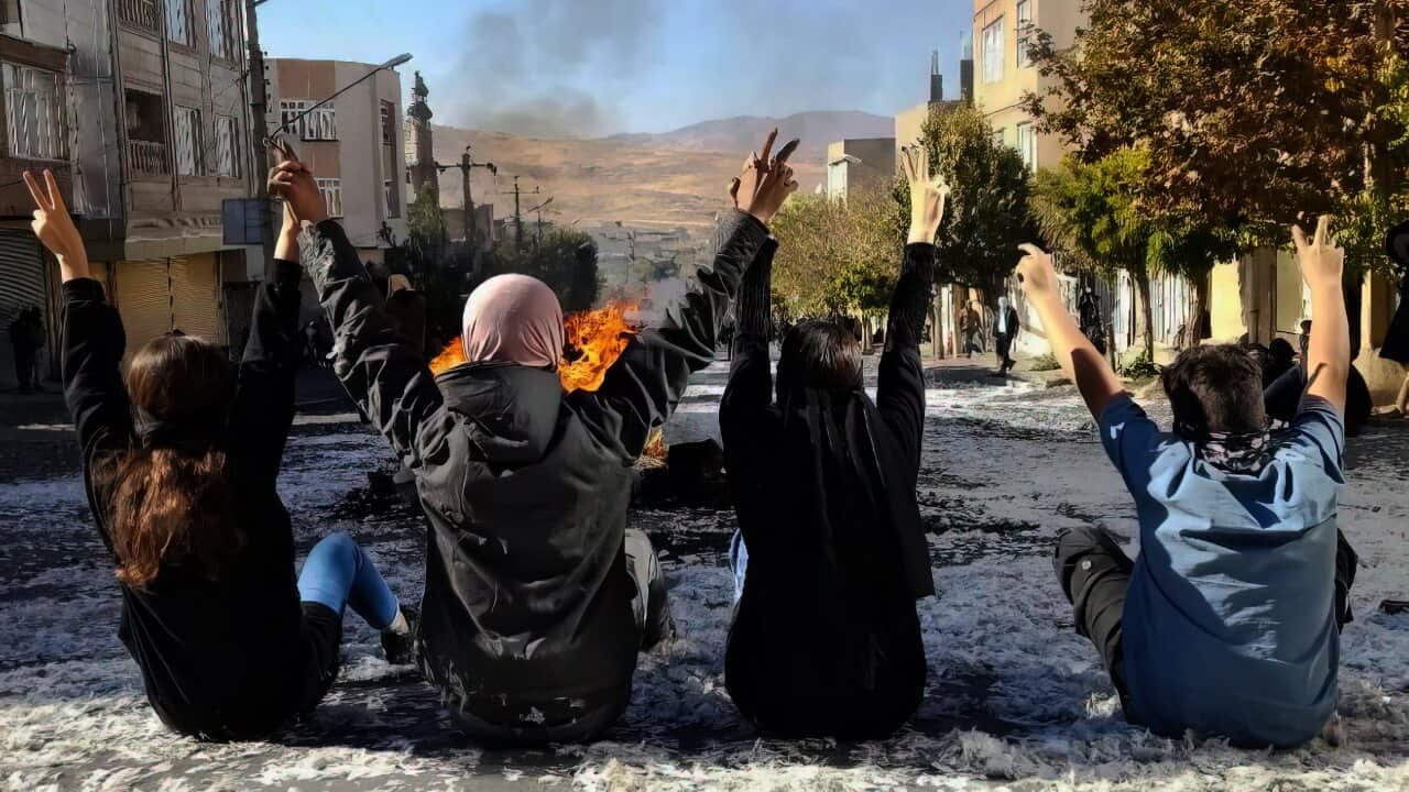 Women sitting on the ground with raised hands