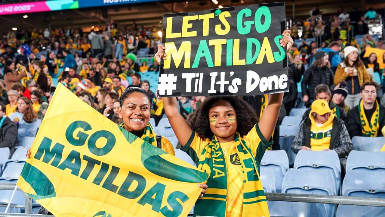 Fans in a stadium hold up signs for the Matildas