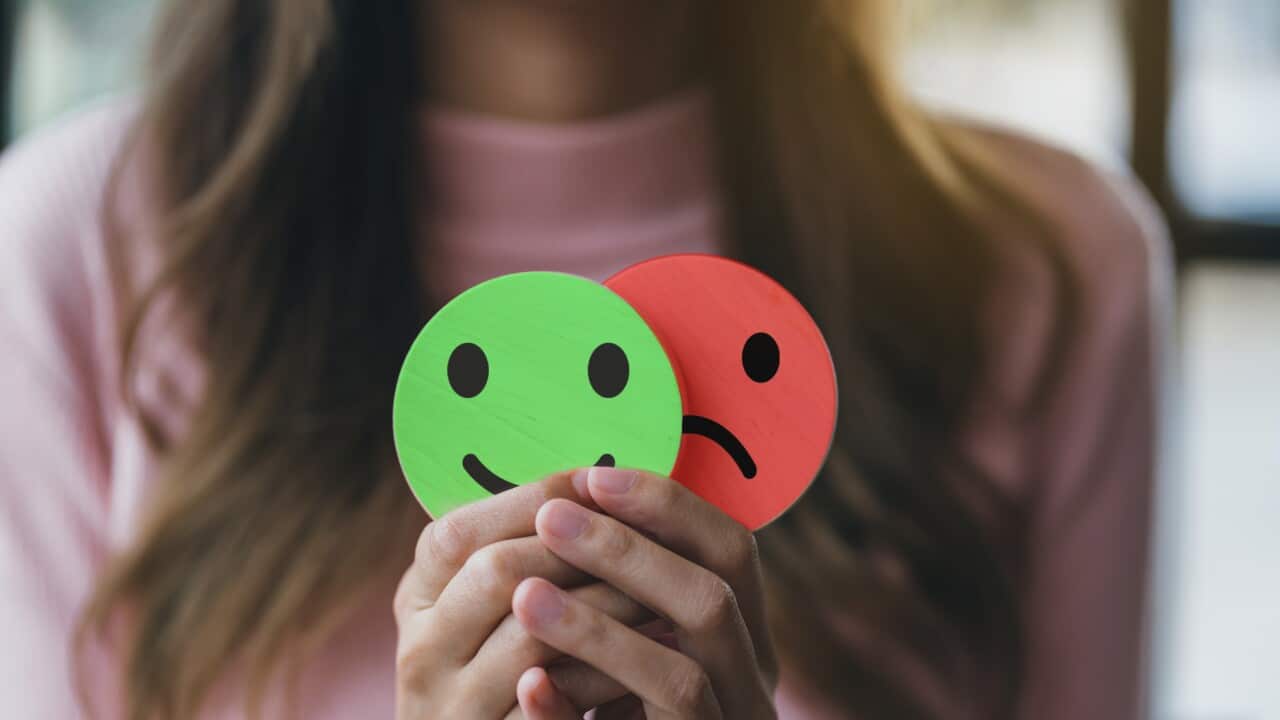 Woman Hands holding sad face hiding or behind happy smiley face, bipolar and depression, mental health concept, personality, mood change, therapy healing split concept.