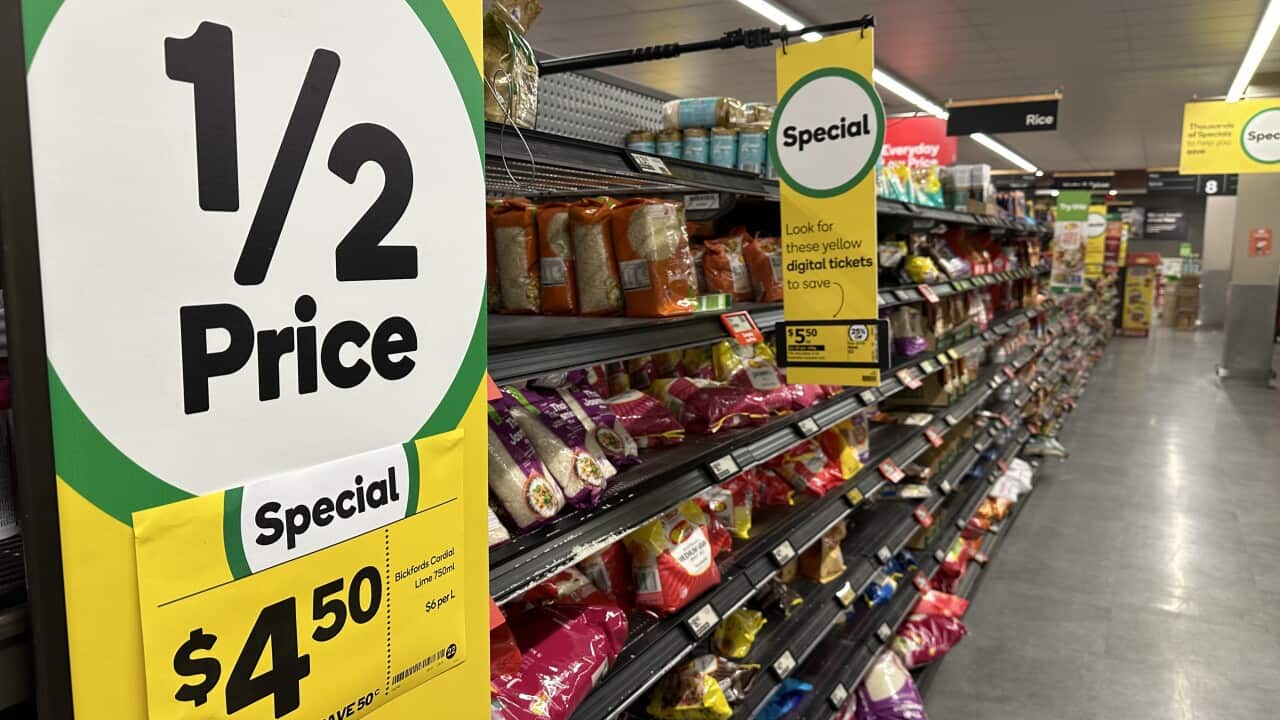 A grocery aisle full of products is seen behind a sales price sign.