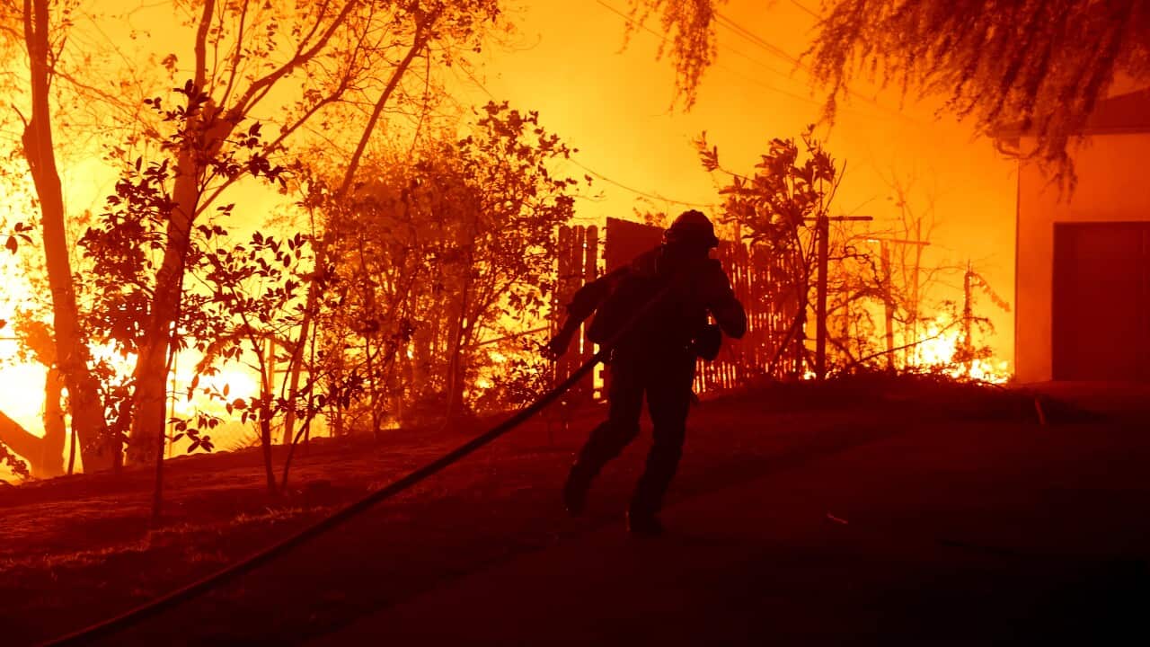 A firefighter running with a hose to fight a fire.