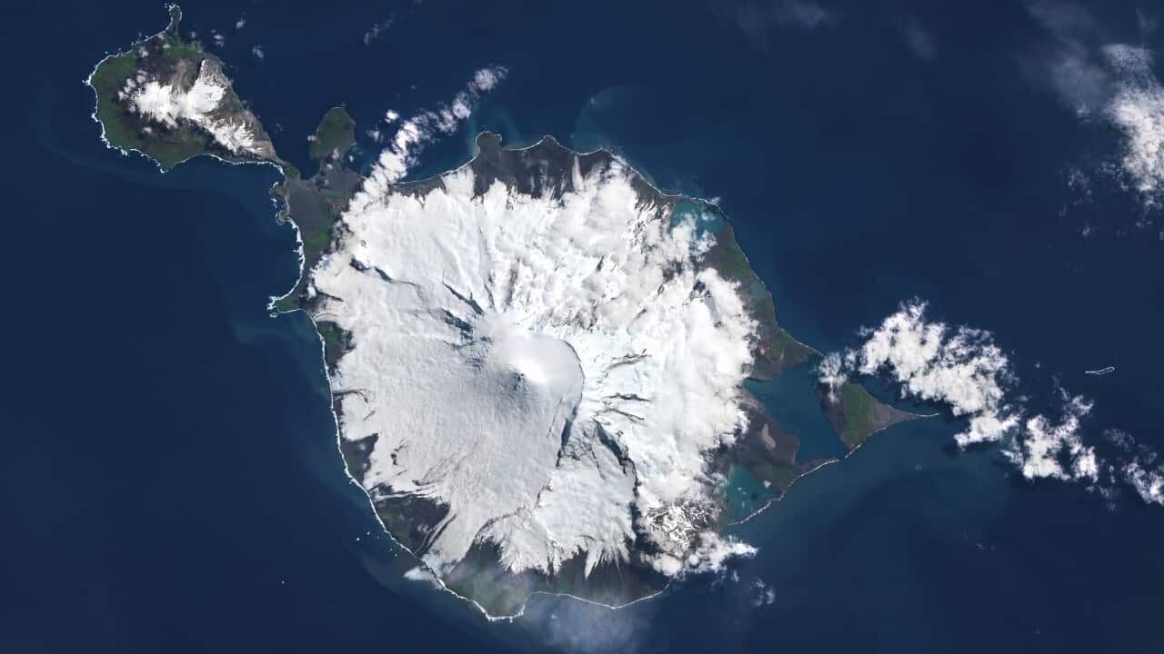 A satellite view of Heard Island. The island is encrusted with snow and surrounded by deep blue ocean.