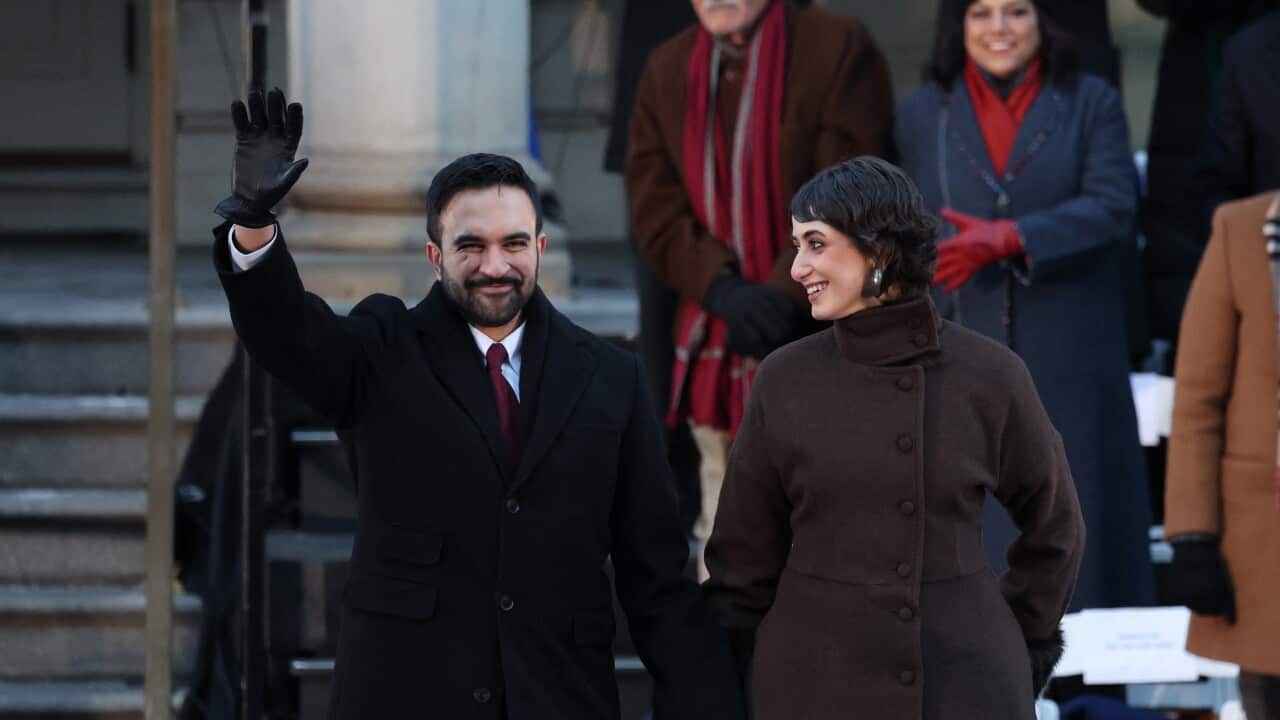 A man waves while holding hands with a woman