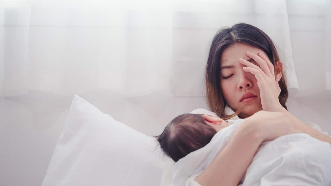 Sad Woman With Baby Lying On Bed At Home