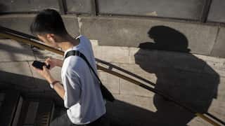 A male walking up stairs while texting on their mobile