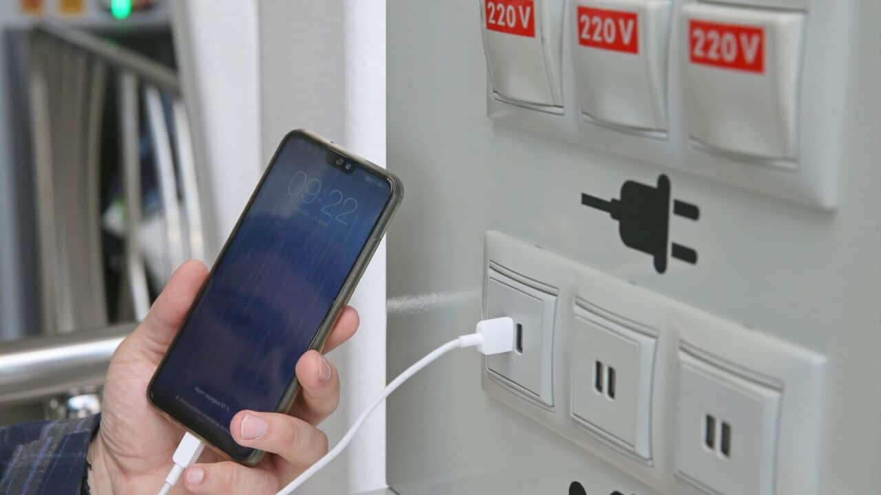 A passenger at a USB mobile phone charging point at a commuter rail line.