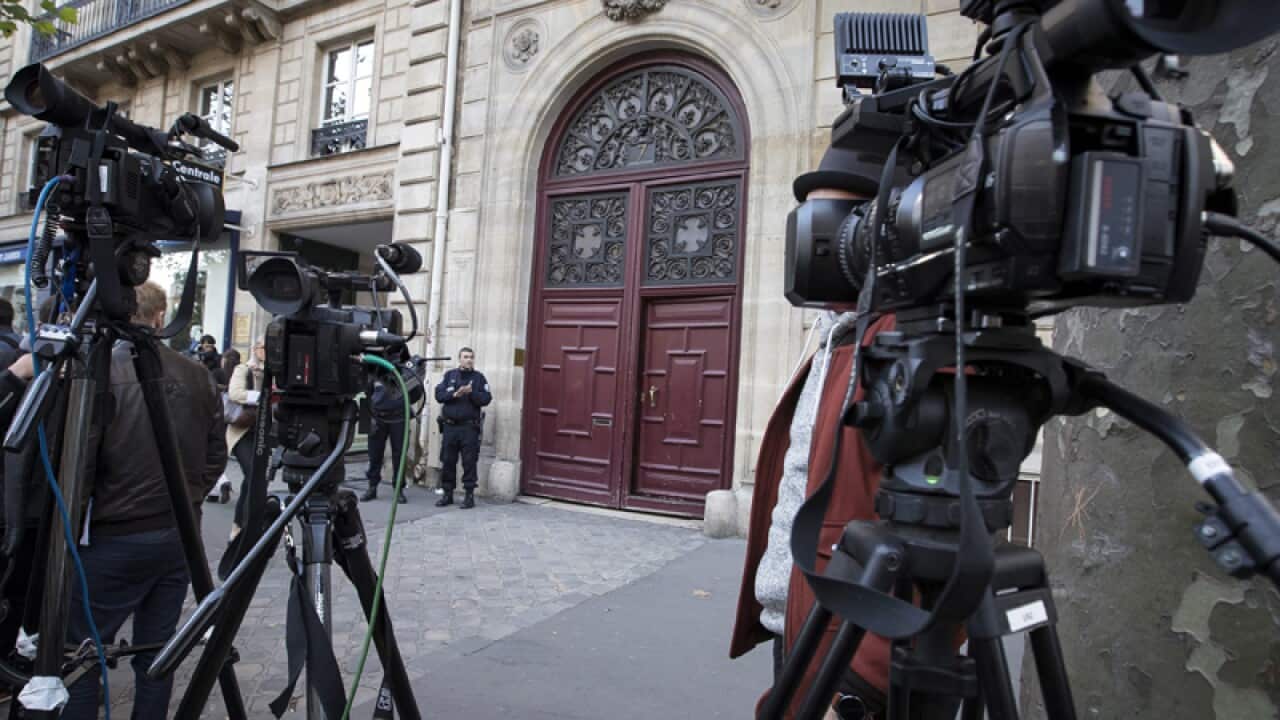 Police stand guard outside the entrance of a building in Paris
