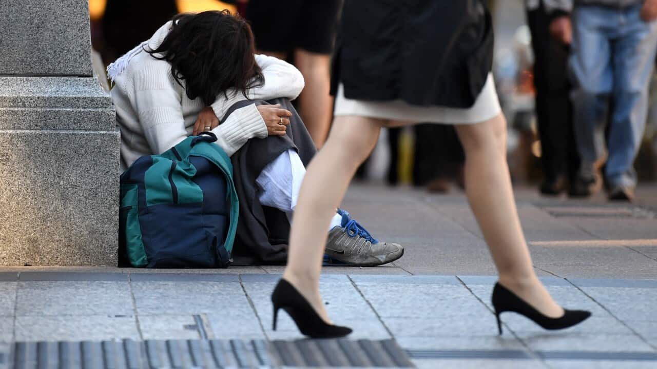 A homeless woman sits on a street corner in central Brisbane