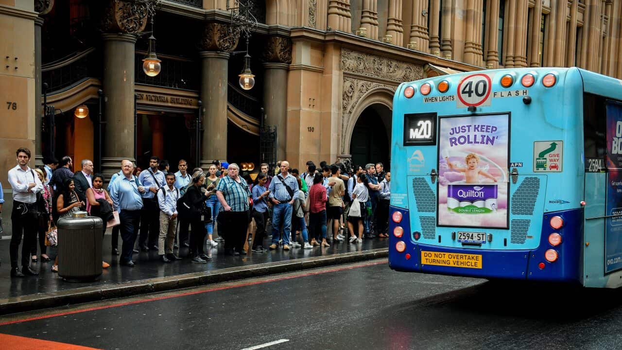 Commuters stand in a line as they wait for buses in Sydney's CBD.
