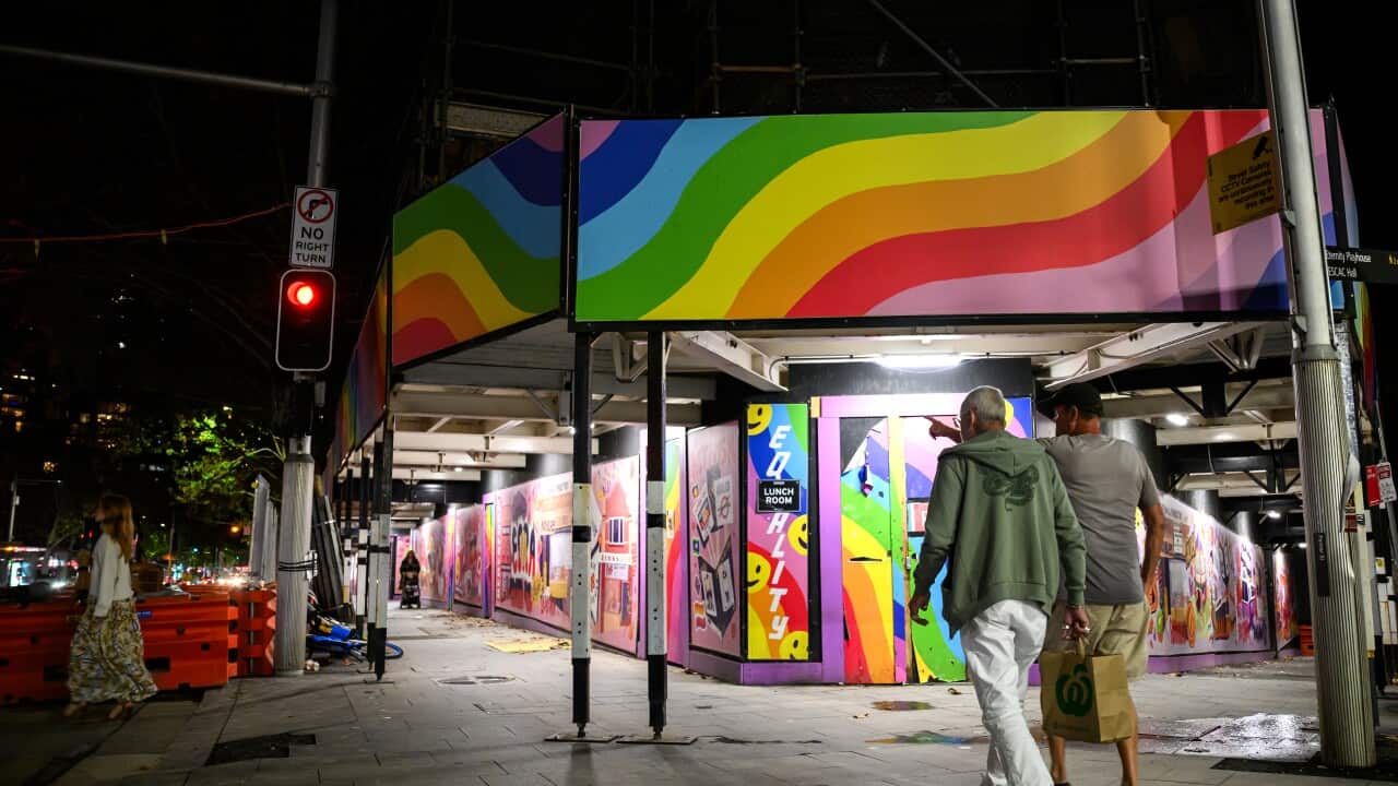 Two men walking under rainbow structure