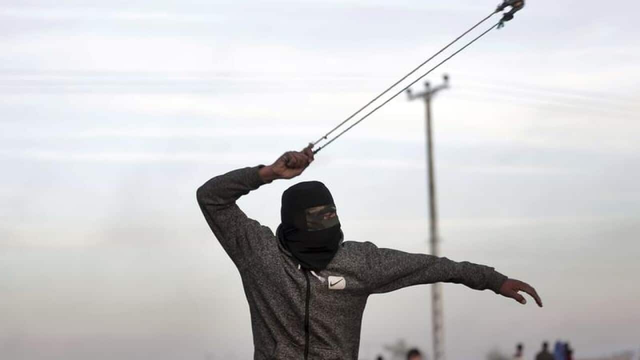 A Palestinian protester slings a stone towards Israeli soldiers.
