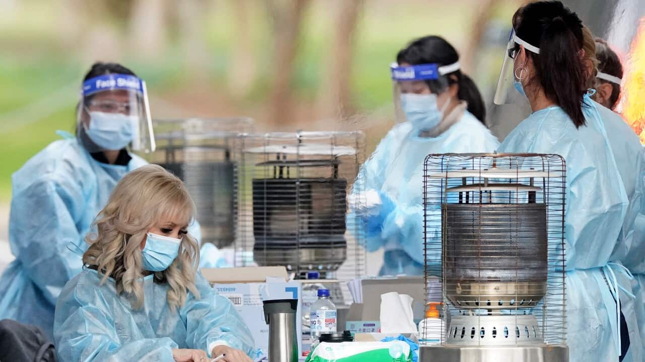 Medical workers look on before taking a sample from a person at a drive-through COVID-19 pop-up testing clinic at the Keilor Community Hub