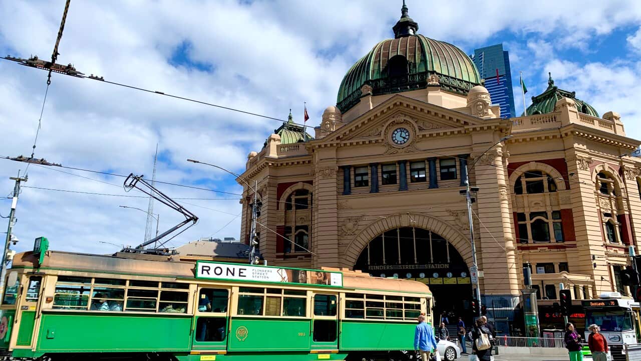 A tram is passing in front of Melbourne Flinders Station. 