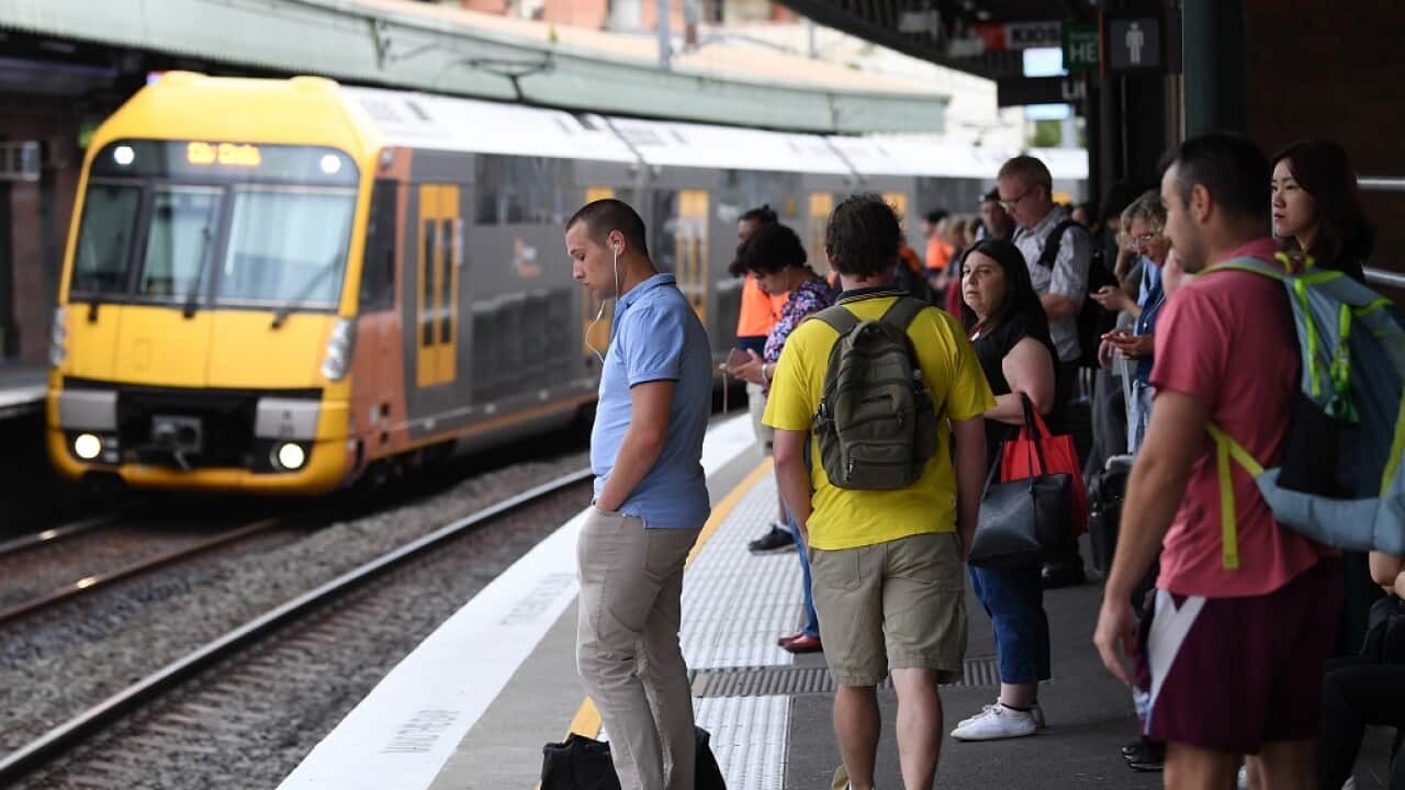 Pictured is a file image of commuters stand on a platform at Strathfield train station in Sydney.