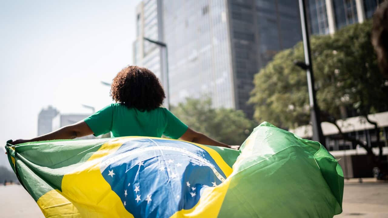 Brazil fan walking and holding a brazilian flag on the city