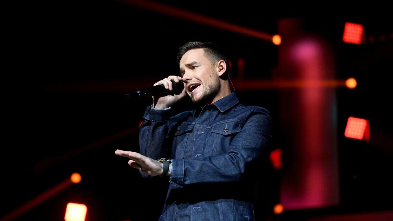 A man in a blue denim jacket is performing on stage.