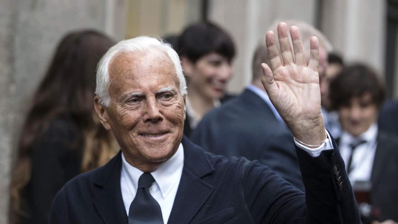 A man wearing a suit, waving
