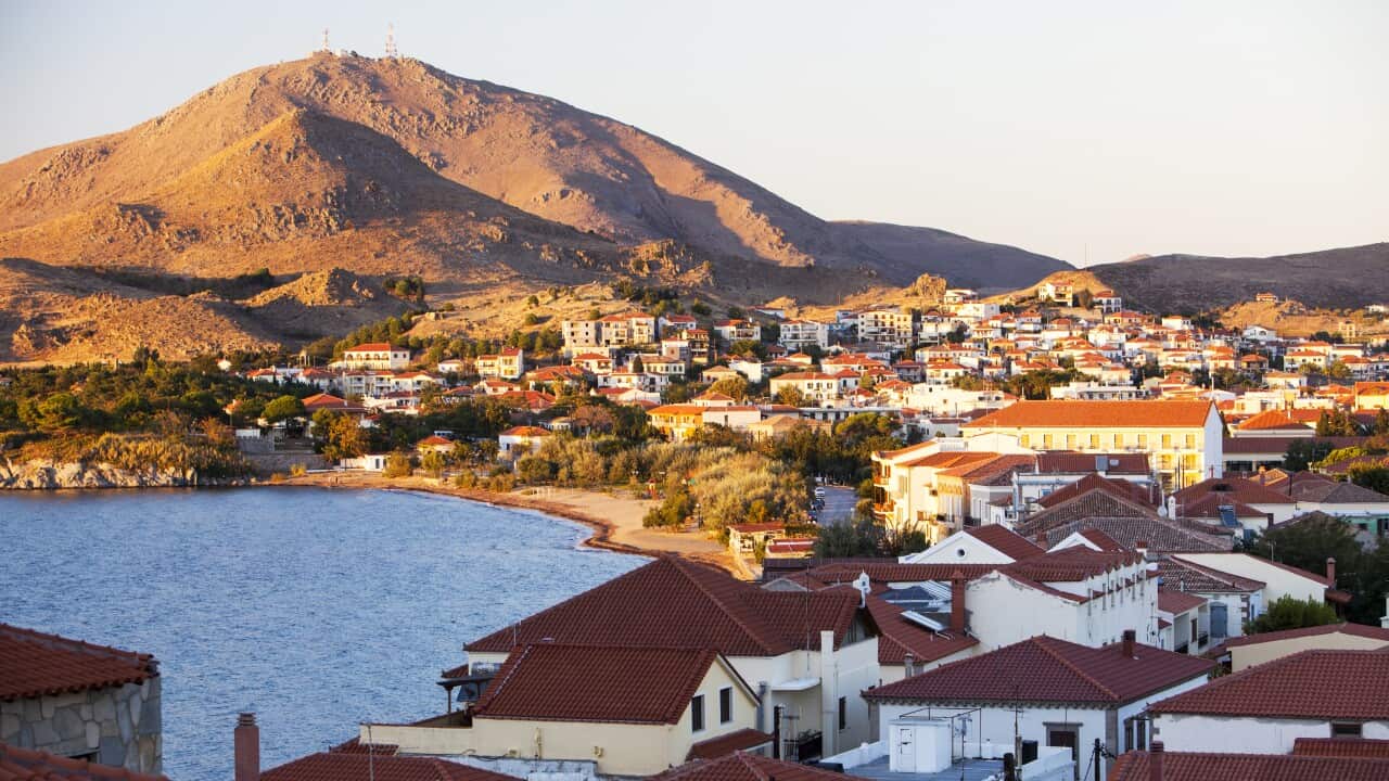 A hill, water, and a town bathed in the evening light