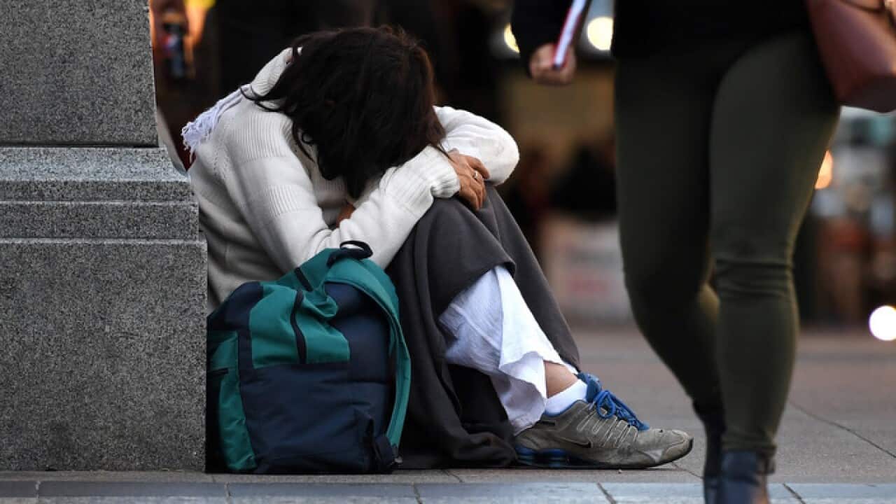 A homeless woman sits on a street corner in central Brisbane, Friday, June 9, 2017. (AAP Image/Dan Peled) NO ARCHIVING