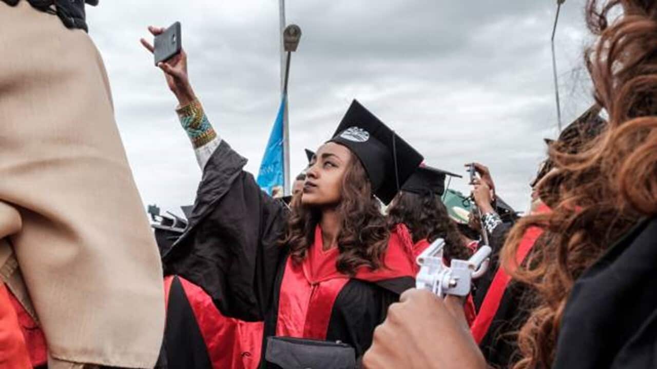 A woman ups her phone as she celebrates for graduation ceremony at Bahir Dar University.jpg