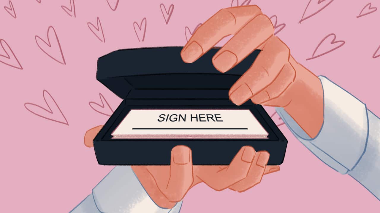 A cartoon image of two hands gripping a wedding ring box - inside it contains a small form that reads “sign here“