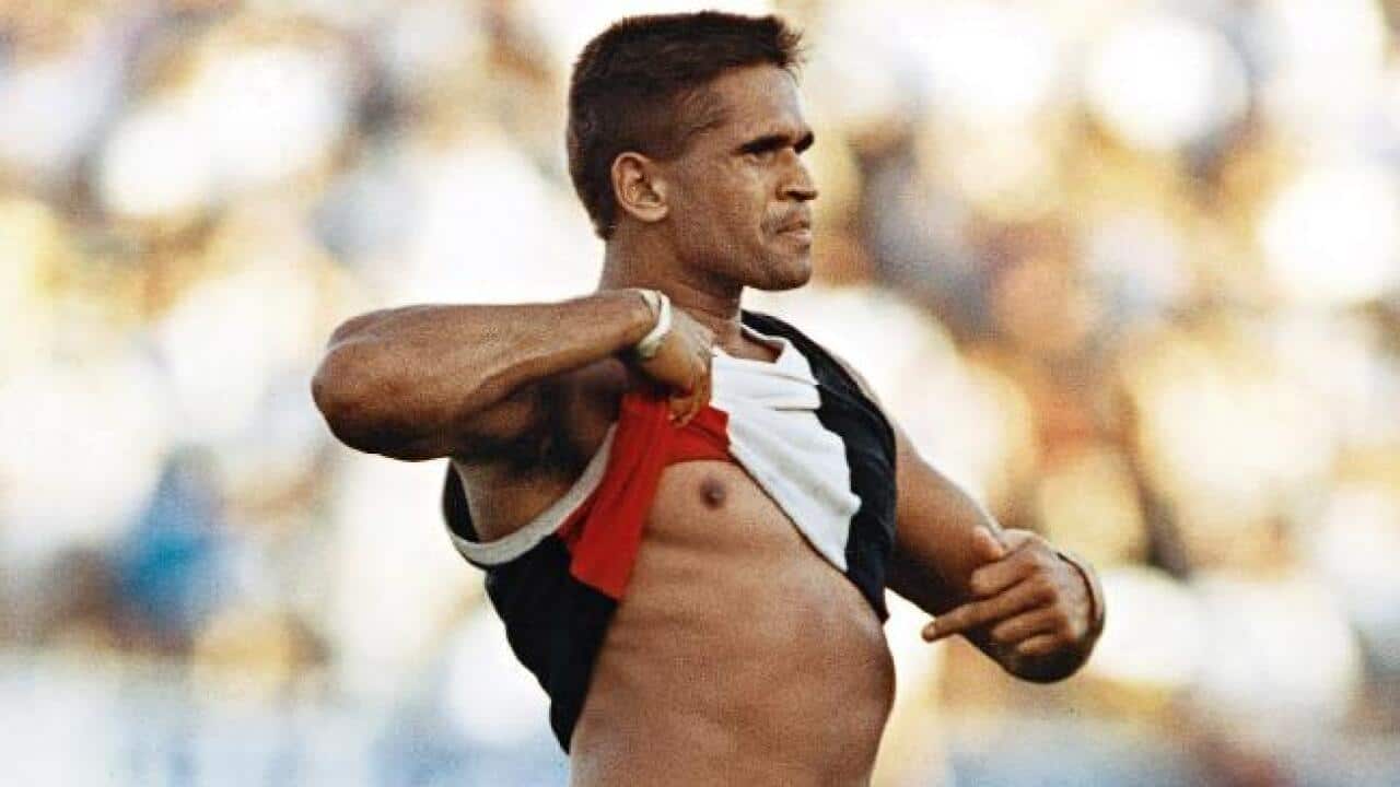 Football player Nicky Winmar lifts his top and points at his stomach in response to racist abuse.