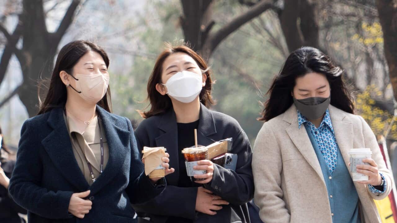 Three South Korean women wallk down a street together