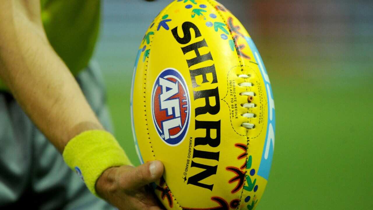 An AFL umpire with an AFL ball
