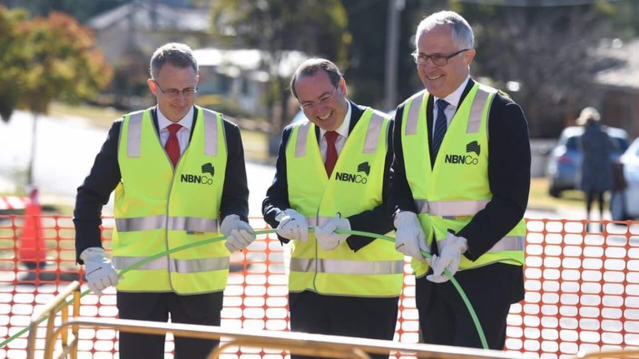 Federal Minister for Communications Malcolm Turnbull (right) lends a hand rolling out NBN fibre at during a visit to an NBN rollout site in Queanbeyan, near Canberra, Wednesday, June 3, 2015. (AAP Image/Lukas Coch) NO ARCHIVING