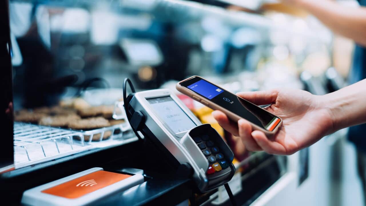 Close up of a woman's hand paying with her smartphone in a cafe, scan and pay a bill on a card machine making a quick and easy contactless payment. NFC technology, tap and go concept