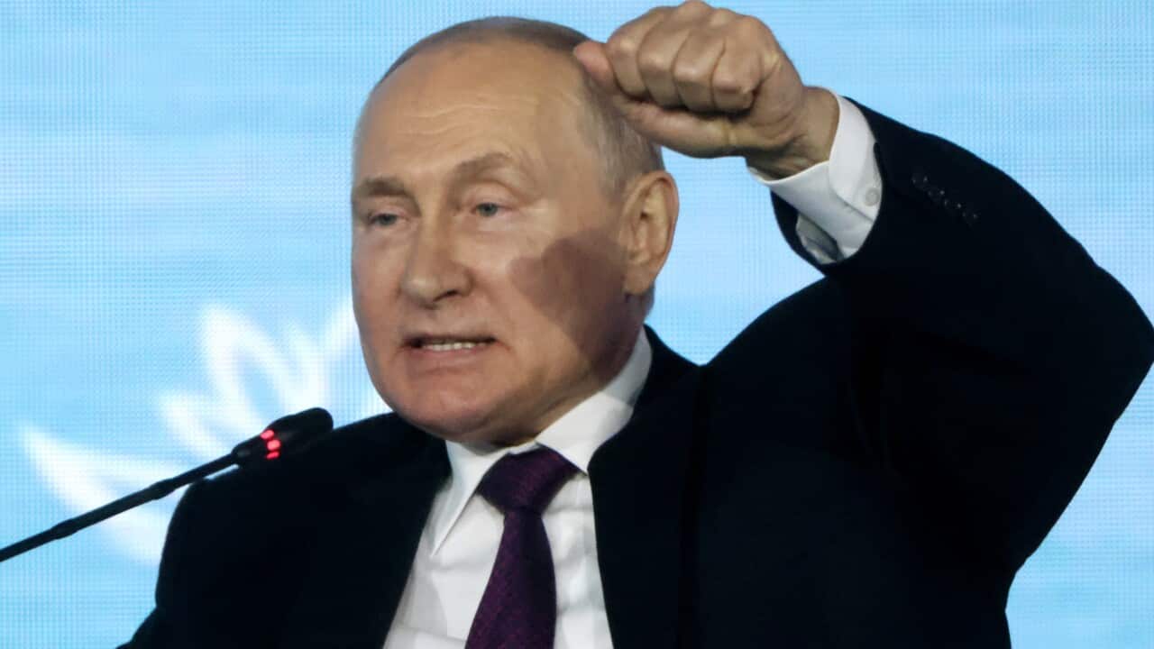 A man seated in a chair speaking into a microphone.