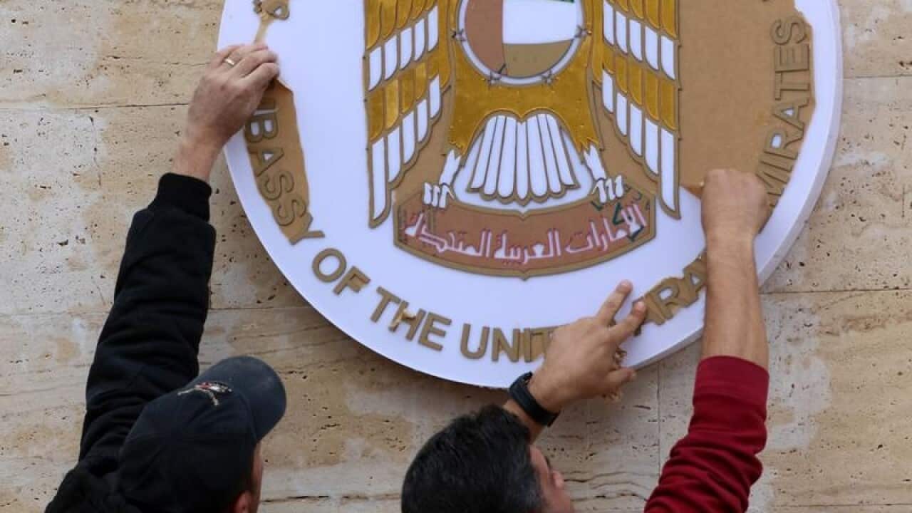Workers clean the metal plaque on the outside of the UAE embassy