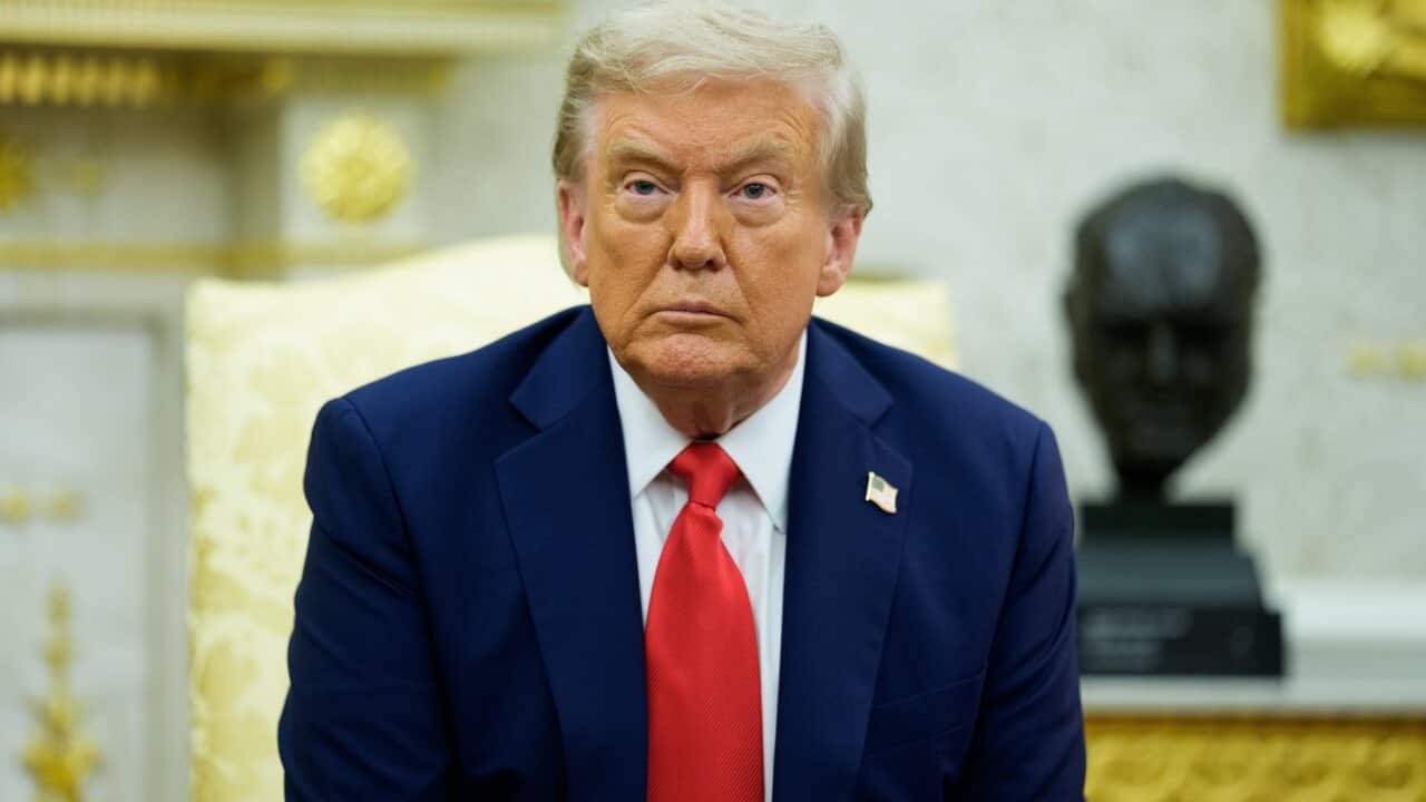 A man in a dark suit with a red tie
