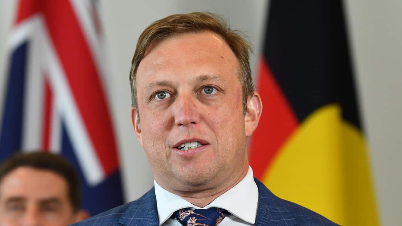 A man in a blue suit and printed tie speaks to the media.