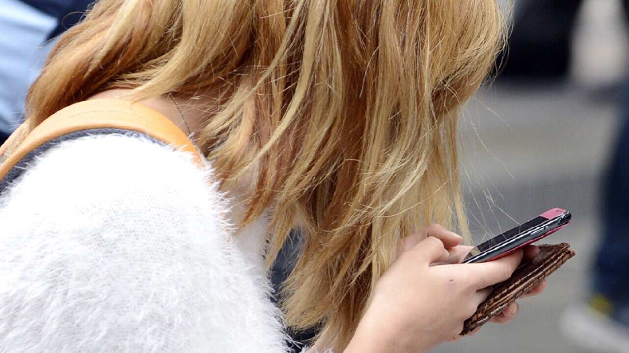 A woman looks at her mobile phone