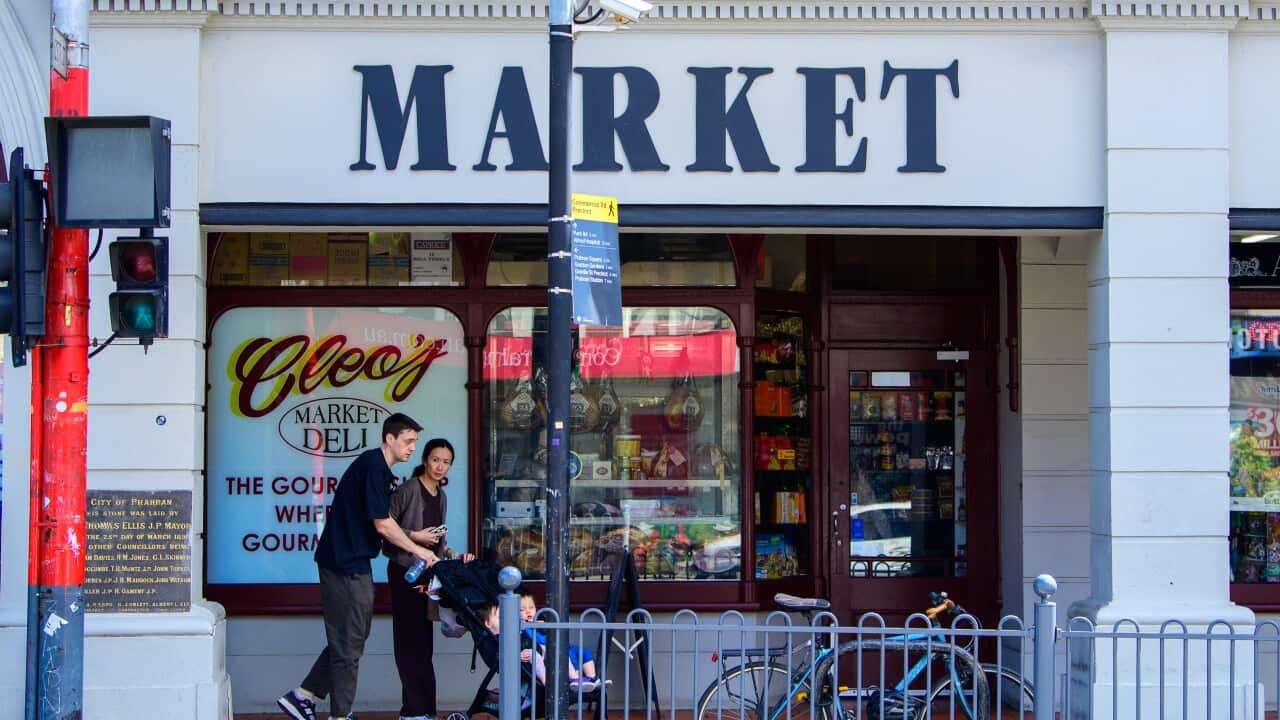 A family pushing a stroller outside a market