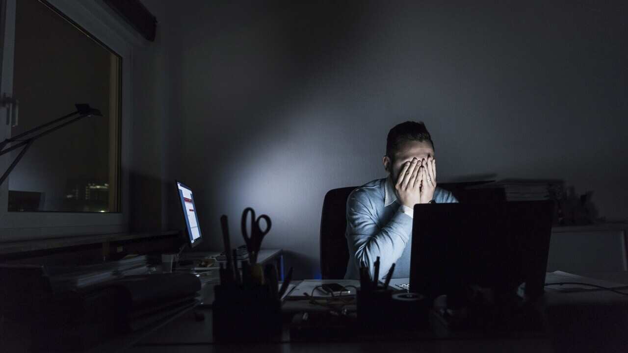 Exhausted businessman sitting at desk in office at night