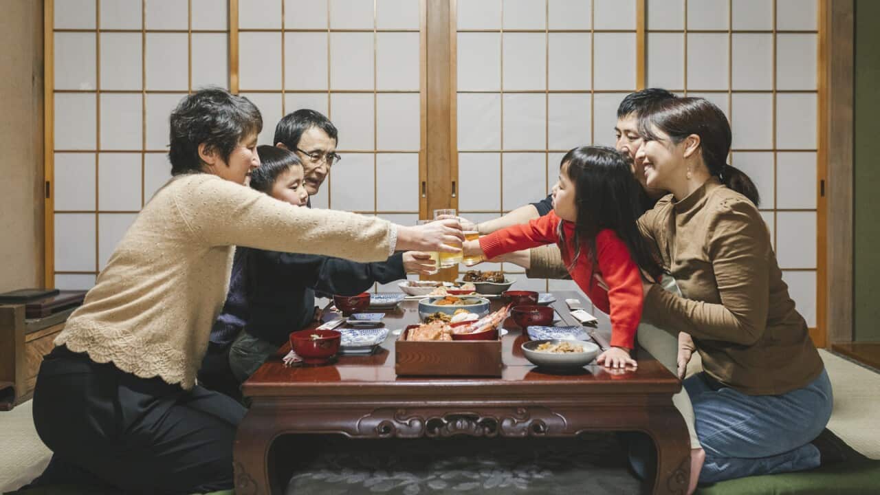 Japanese mulit generation family drinking a toast before eating Osechi Ryori, Japanese New Year dishes, on the dining table in Japanese room