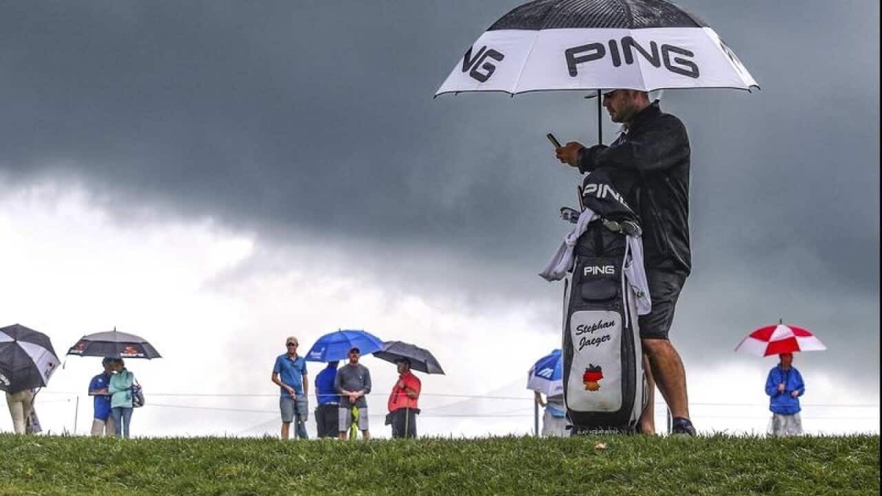 A caddie for golfer Stephan Jauger holds an umbrella.