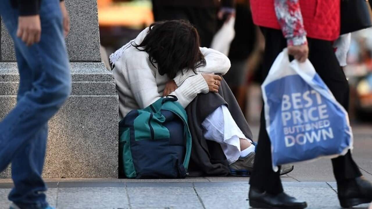 A woman sits on a street corner in central Brisbane
