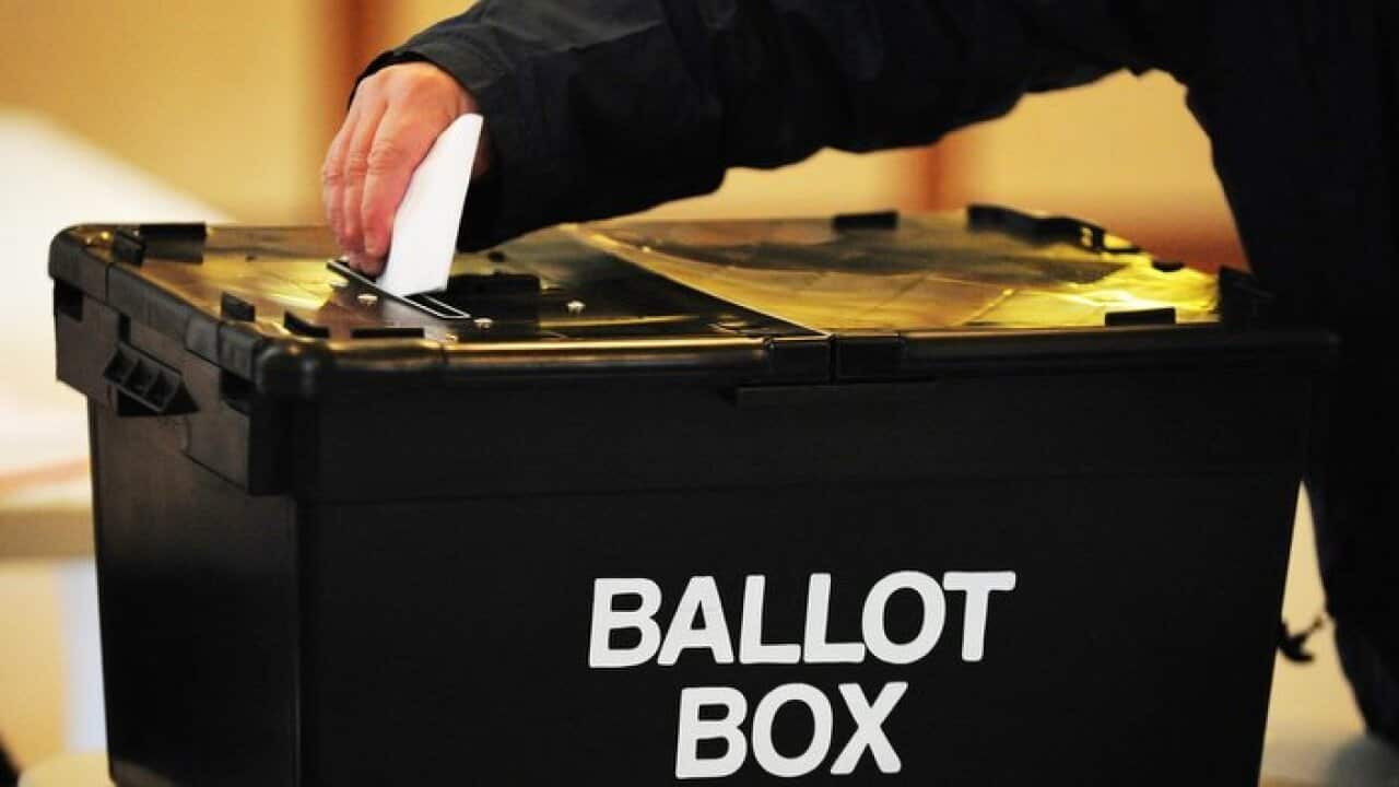 A voter placing a ballot paper in the ballot box at a polling station
