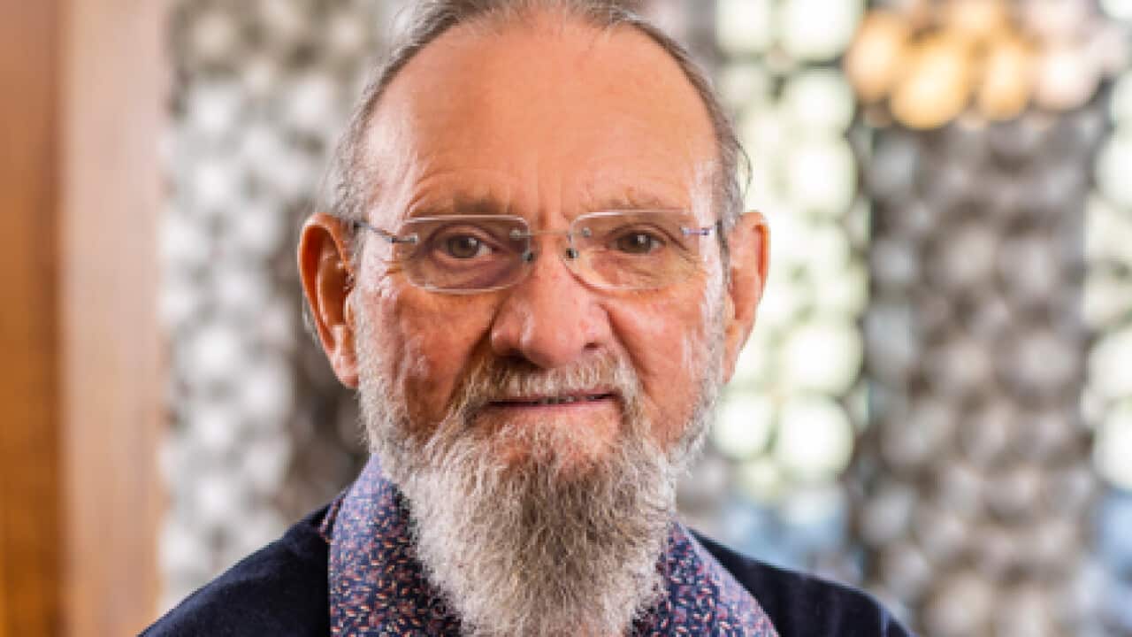 an older man with a long grey beard wearing glasses smiling at the camera