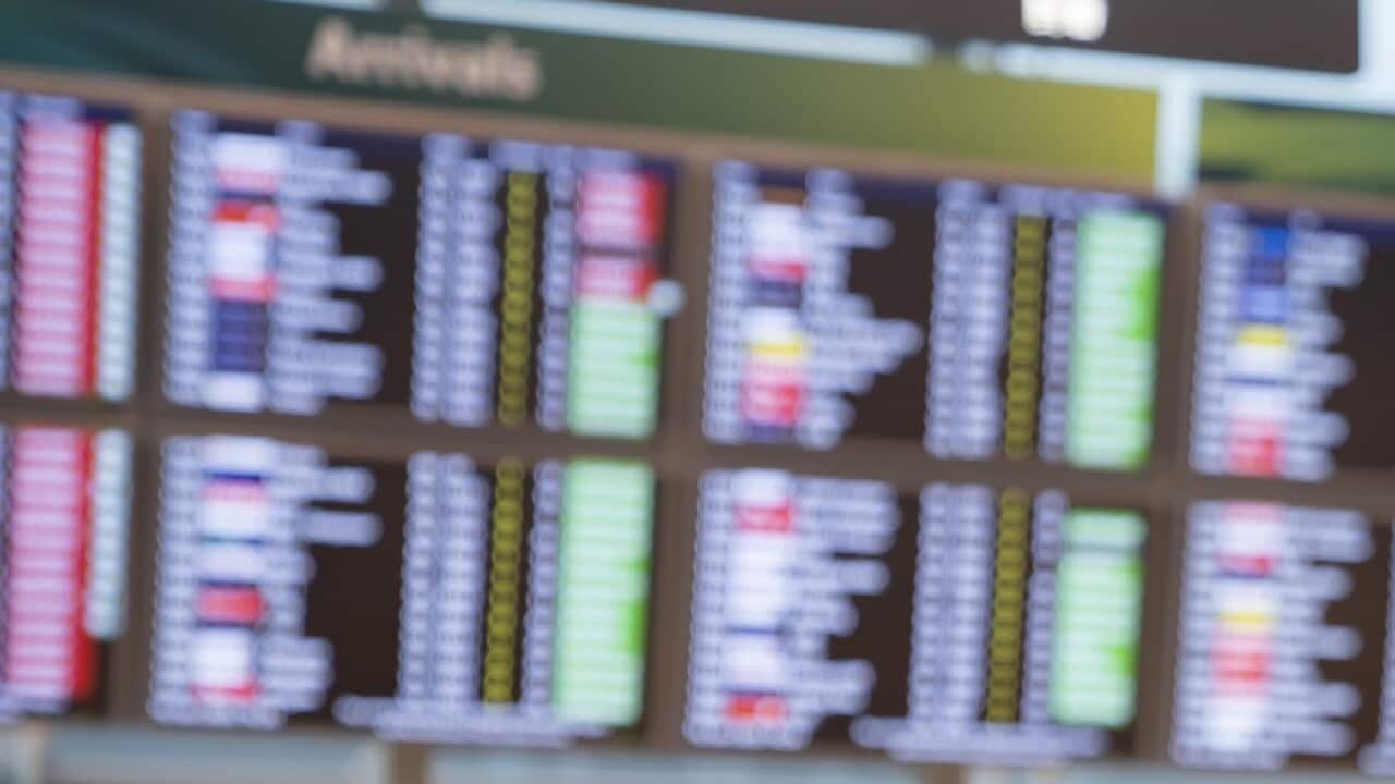 Female passenger looking flight schedule on the digital board in the terminal