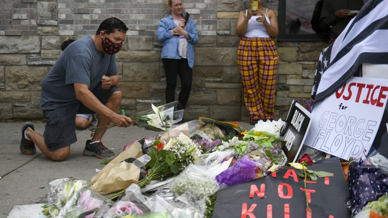 A supporter places flowers at a makeshift memorial near the scene of the arrest of George Floyd, who later died in police custody.