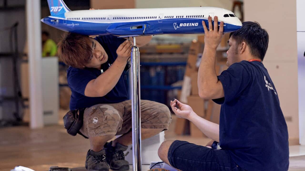 Workers install a model Boeing plane at a show