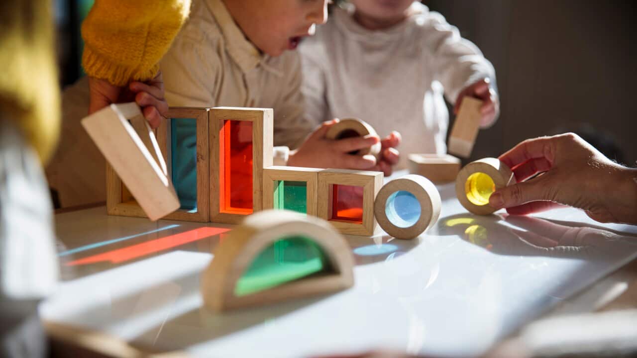 Children playing with colourful blocks on a table.