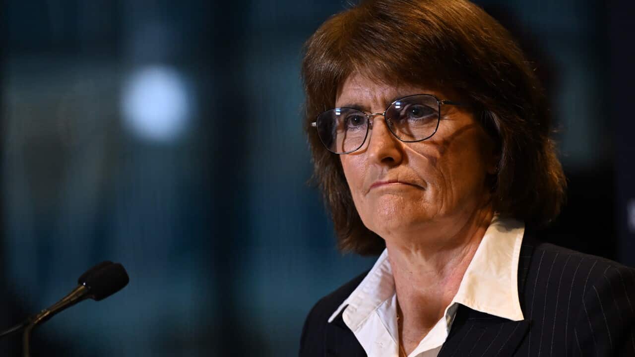 A woman standing at a lectern in front of a microphone.